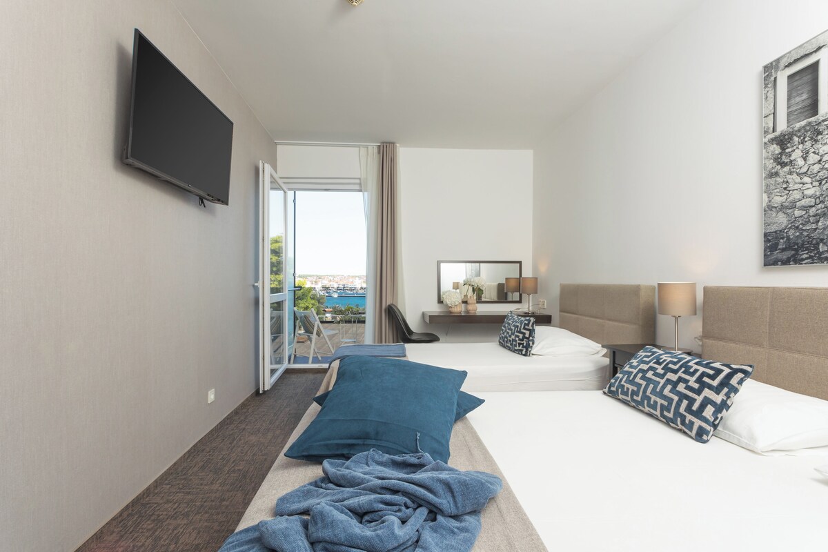 A hotel room with a bed, a television, a window, and a view of the outside.