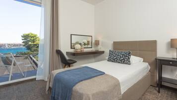 Habitación de hotel con cama, escritorio, silla y vista al mar.