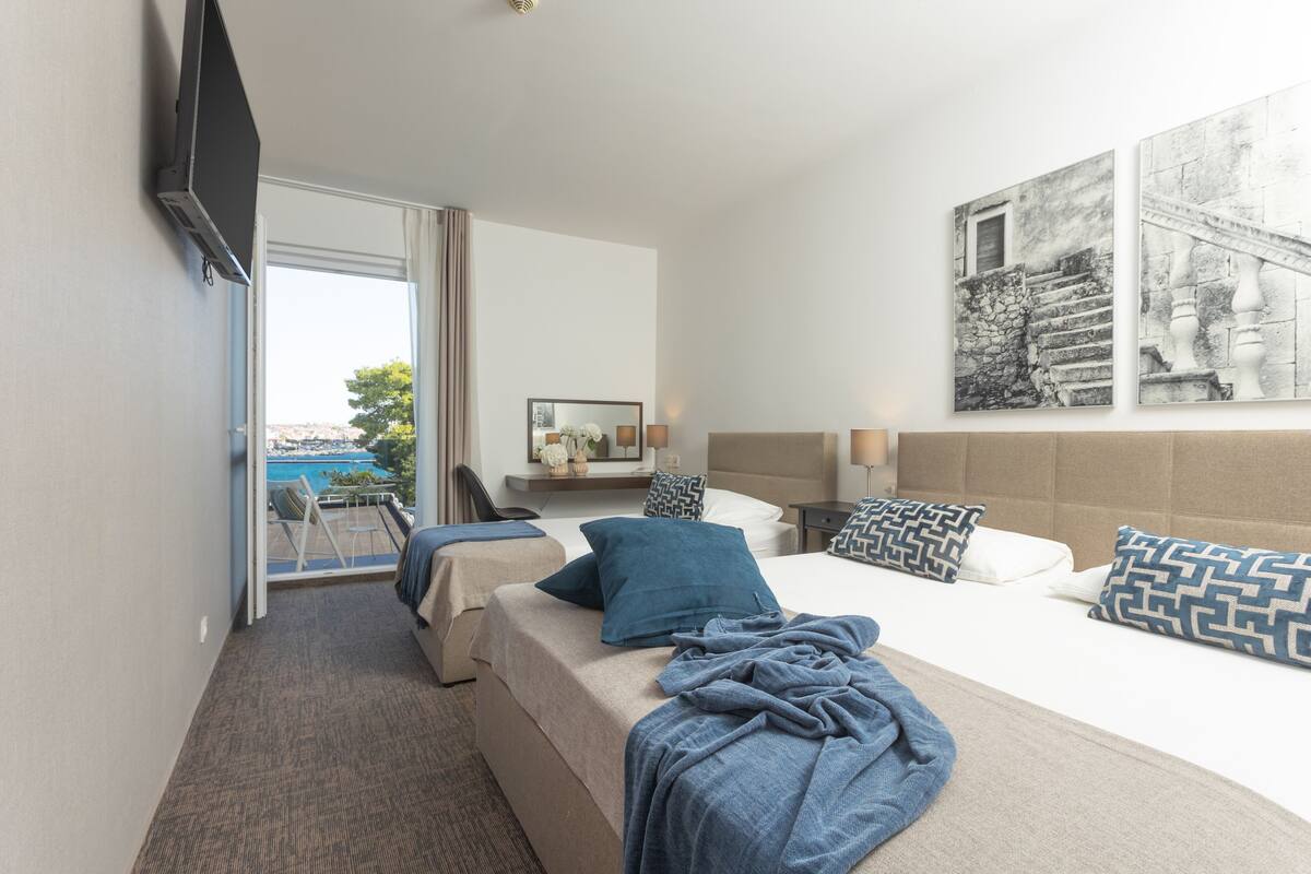 Ein Hotelzimmer mit Bett, Schreibtisch, Stuhl und Meerblick.