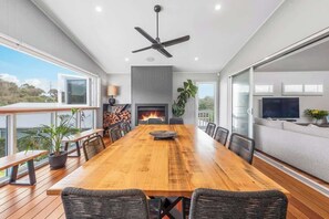 A spacious dining area with a long wooden table, comfortable chairs, and a ceiling fan.