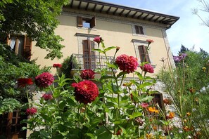 A building with a beige facade, wooden shutters on windows, and a balcony with a wrought iron railing. - 1 Bedroom Apartment in Umbria (Umbria)