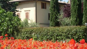 Un edificio con tetto in tegole e un giardino con fiori rossi in primo piano.