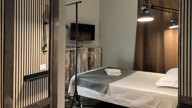 A hotel room with a bed, a desk, a flat-screen TV, and a standing lamp. - Hotel Calypso (Milan)