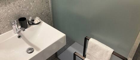 Une salle de bain avec un lavabo blanc, une serviette noire et un miroir au mur.