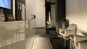 A modern hotel lobby with a reception desk, a glass partition, and a seating area with chairs. - Hotel Calypso (Milan)
