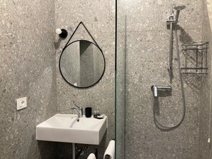 Habitación básica con 2 camas individuales | Baño | Cabezal de ducha tipo lluvia, toallas, jabón y champú