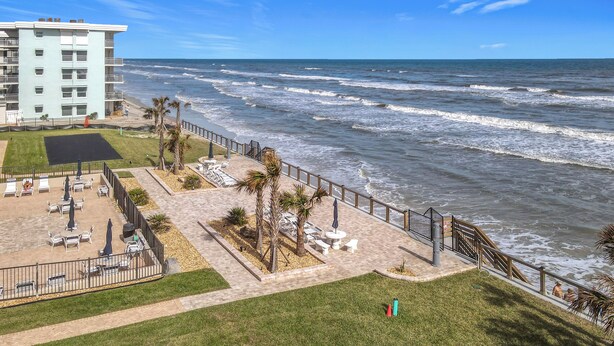 A beachfront patio with outdoor seating, a pool, and a view of the ocean.