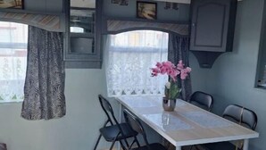 Un coin repas comprenant une table, des chaises, un vase avec des fleurs et une fenêtre avec des rideaux.