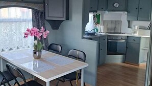 Une cuisine compacte avec des meubles gris, un îlot central et un coin repas comprenant une table et des chaises.