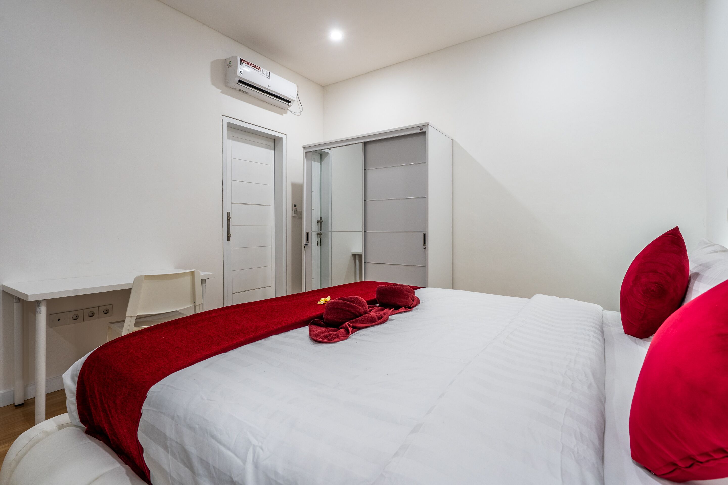 A bedroom with a bed, a desk, and a wardrobe.