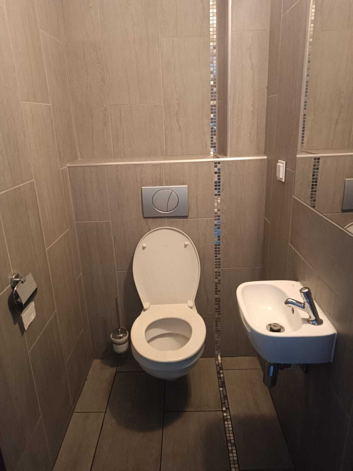 A bathroom with a toilet, sink, and tiled walls.