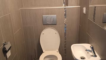 A bathroom with a toilet, sink, and tiled walls.