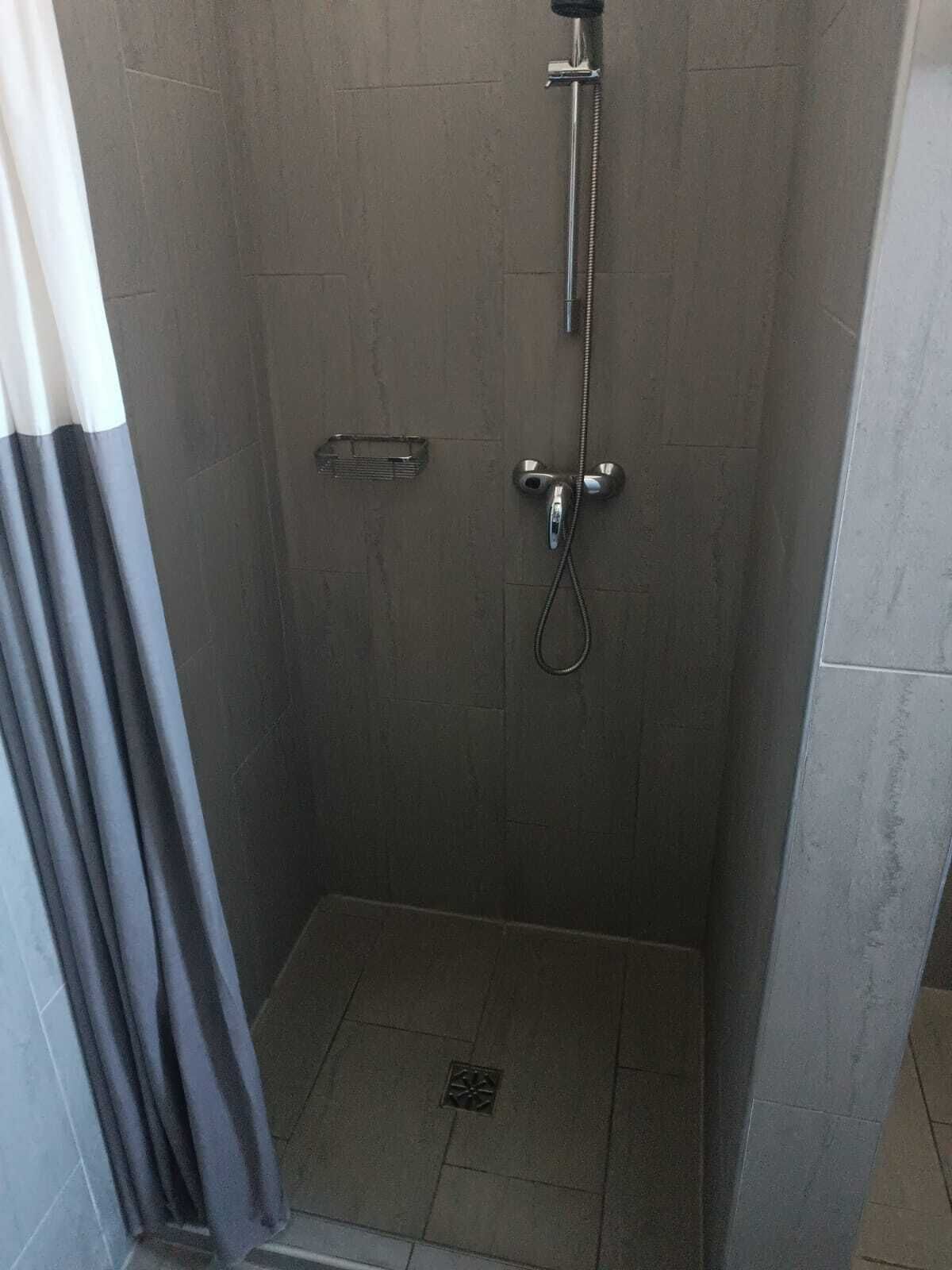 Eine Dusche mit Handbrause und Armaturen an der Wand.