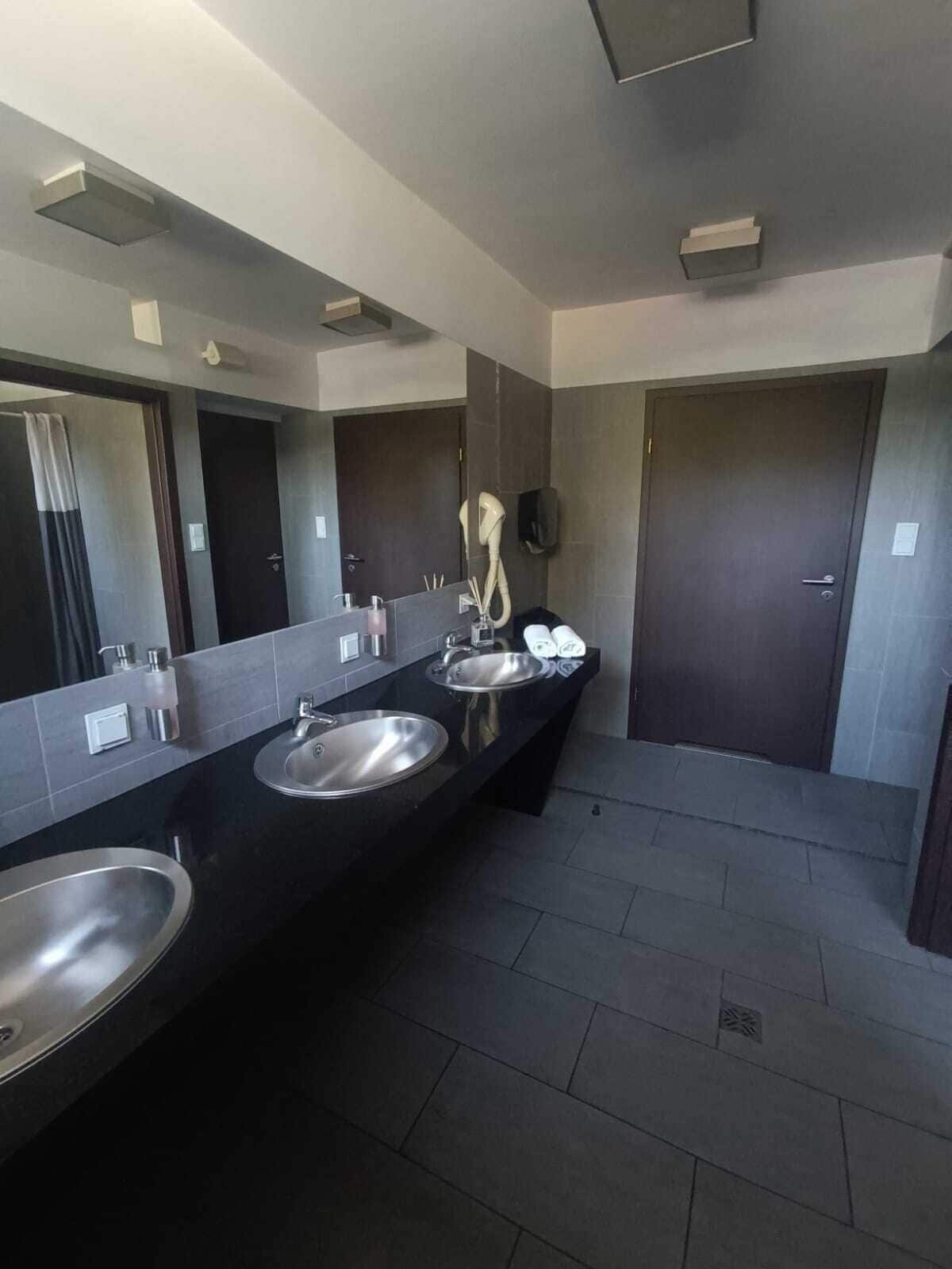 Un baño moderno con dos lavamanos, un espejo grande y un secador de pelo.