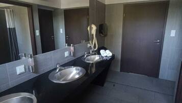 Un baño moderno con dos lavamanos, un espejo grande y un secador de pelo.
