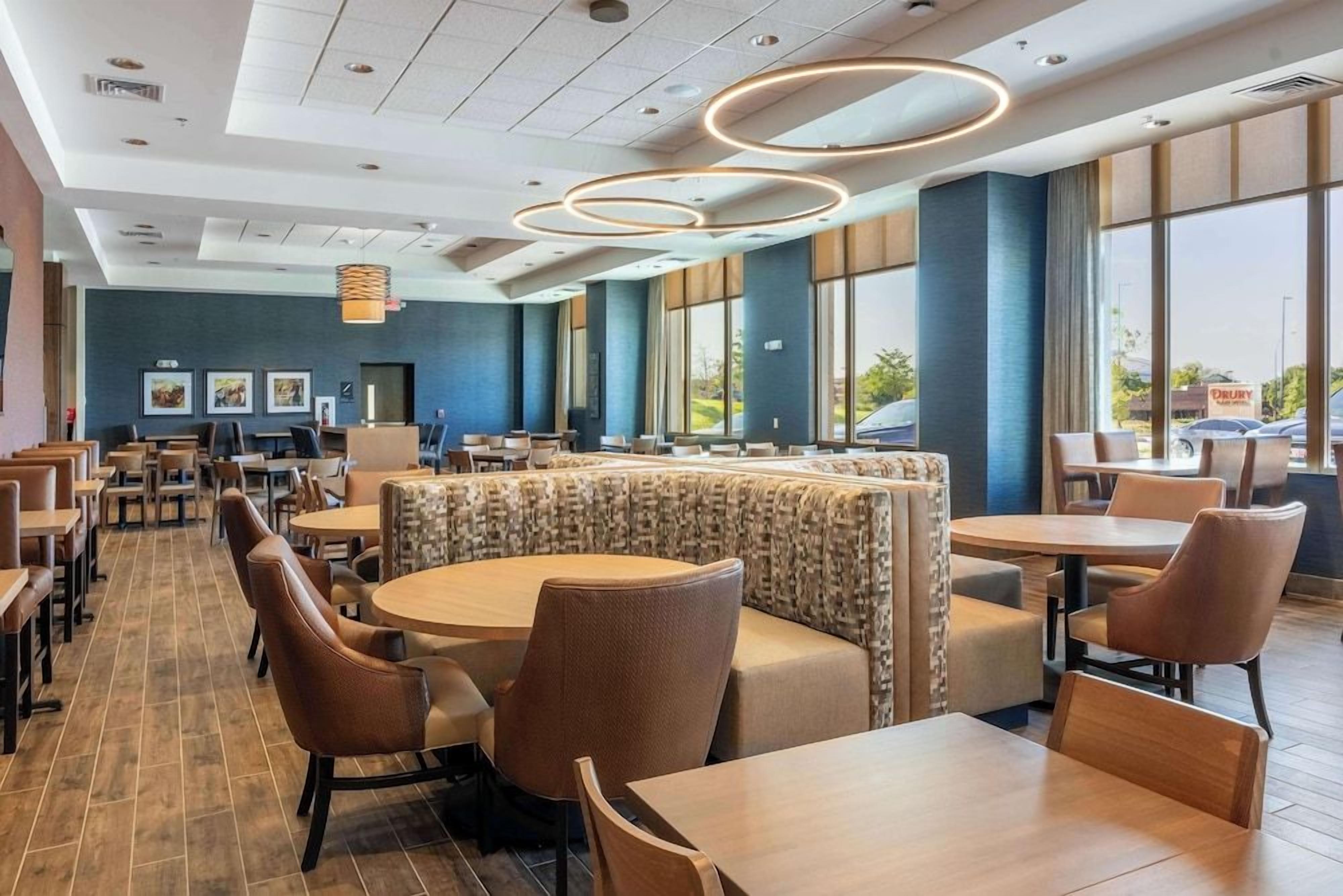 Un comedor de hotel con mesas redondas, cabinas y vistas al exterior.