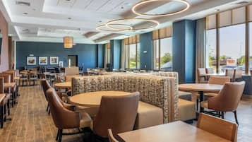 Un comedor de hotel con mesas redondas, cabinas y vistas al exterior.