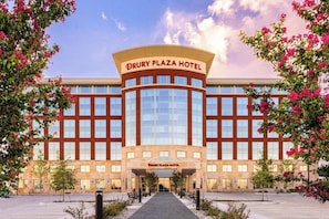 A hotel with a prominent entrance, large windows, and a clear sky.