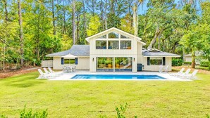 Une maison moderne avec une piscine, entourée d’une végétation luxuriante.