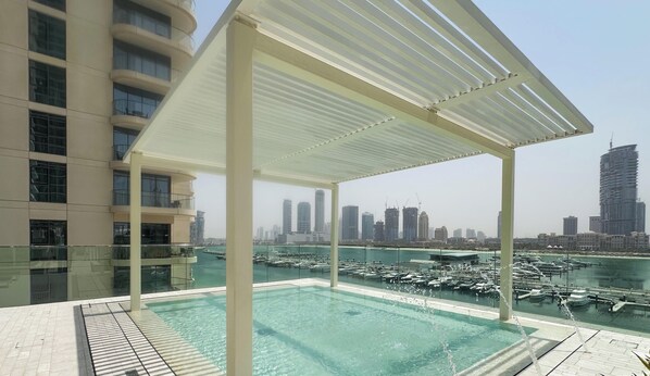 Piscina en la azotea con vistas a un puerto deportivo y al horizonte de la ciudad.