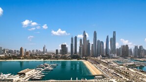 A coastal cityscape with a marina filled with boats, a sandy beach, and a dense cluster of modern skyscrapers. - LUX  Luxury Sunrise Beachfront Suite 2 (Dubai)