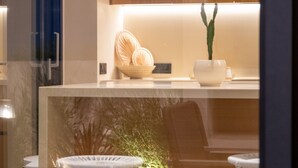 Una cocina moderna con armarios de madera, encimera blanca y una pequeña planta en maceta.