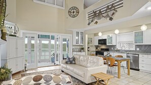 A spacious living area with a white sofa, a dining table, and a kitchen with modern appliances.