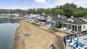 A beachfront property with multiple houses, a swimming pool, and a sandy beach.