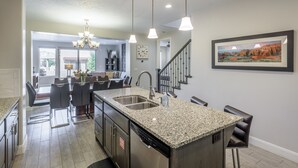 Una cocina moderna con encimeras de granito, electrodomésticos de acero inoxidable y una isla central.