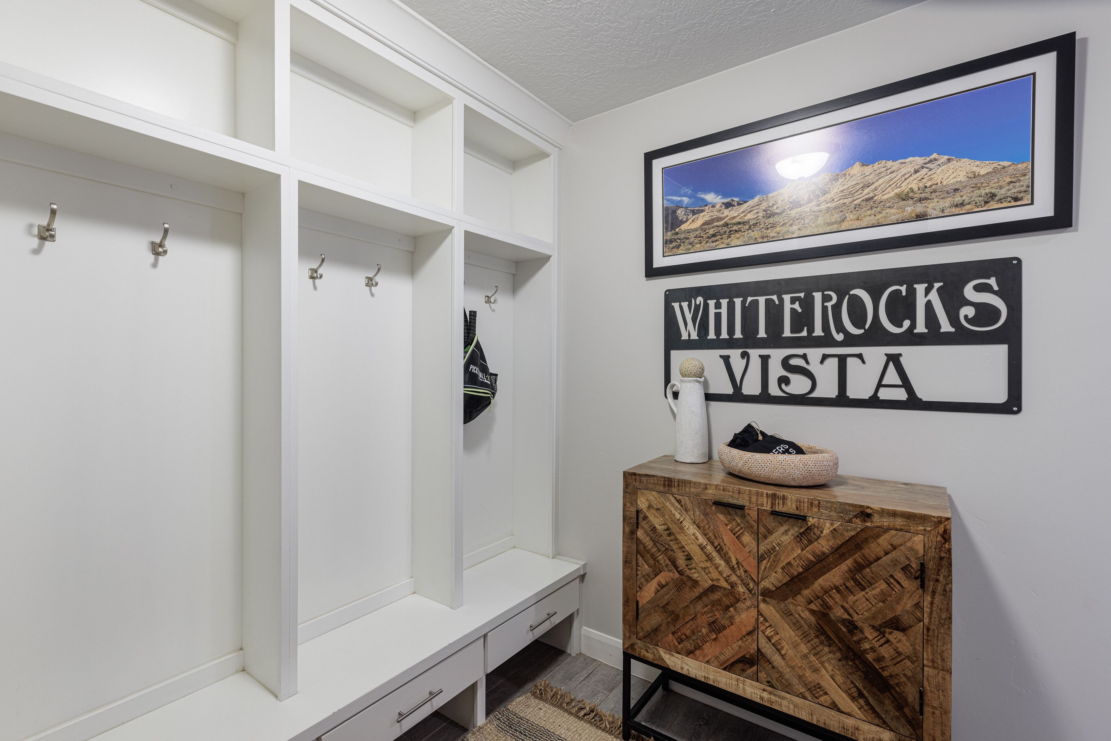 Un meuble de rangement blanc doté de crochets, une armoire en bois et un panneau encadré portant l’inscription « WHITEROCKS VISTA ».