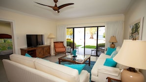 A living room with a sofa, coffee table, TV, and a ceiling fan.