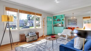 Ein Wohnzimmer mit blauem Sofa, Couchtisch, Lampe und Blick ins Freie.