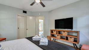 Ein Hotelzimmer mit Bett, Fernseher, Deckenventilator und einem Holzboden mit Körben.