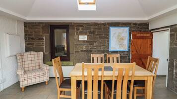 A dining area with a stone wall, a map, and a plaid armchair.