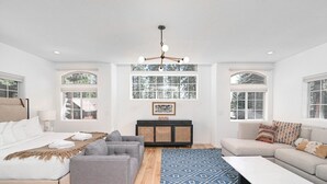 A modern bedroom with a bed, grey sofa, and a blue patterned rug.