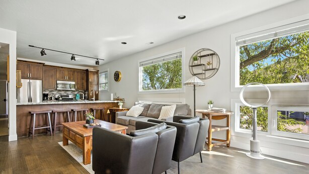 A modern kitchen with a central island, a dining area with a wooden table, and a seating area with a sofa and chairs. - 5 minute walk to PCMR! Stylish condo in the heart of town! Hot Tub, EZ Bus. (Park City)