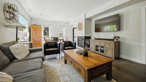 A modern living room with a sofa, chairs, a wooden coffee table, and a TV mounted on the wall. - 5 minute walk to PCMR! Stylish condo in the heart of town! Hot Tub, EZ Bus. (Park City)