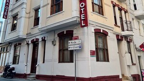 Un immeuble de trois étages sur lequel on peut voir une grande enseigne rouge avec l’inscription « DIMORA HOTEL ».