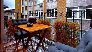 Un espace extérieur aménagé avec une table et des chaises en bois, entouré de plantes décoratives et doté d’un sol à motifs.