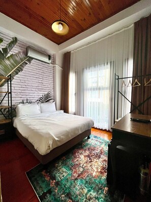 A bedroom with a bed, a desk, a chair, a hanging plant, and a large window with curtains. - Dimora Kadıköy (Istanbul)