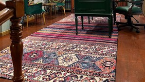 Une pièce avec un bureau vert, un tapis à motifs, une chaise verte et une carte du monde accrochée au mur.