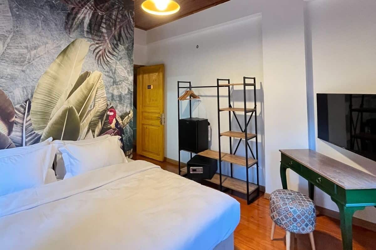 A bedroom with a bed, a desk, a chair, a TV, and a wooden ceiling.