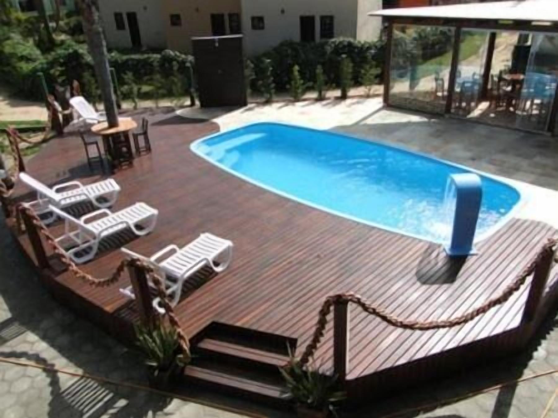 An outdoor swimming pool with lounge chairs and a barbecue grill.