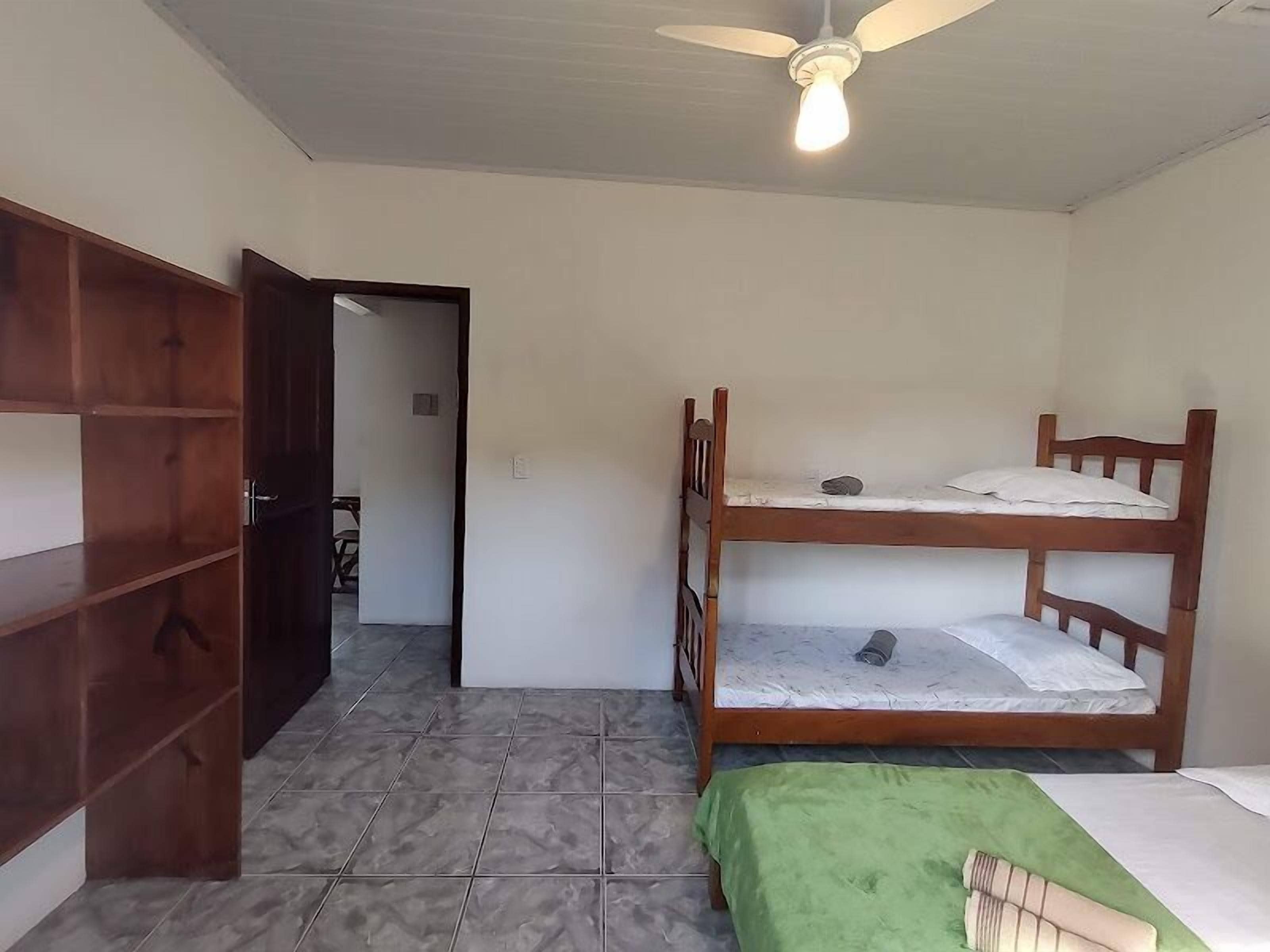 A room with a bunk bed, a wooden wardrobe, and a ceiling fan.