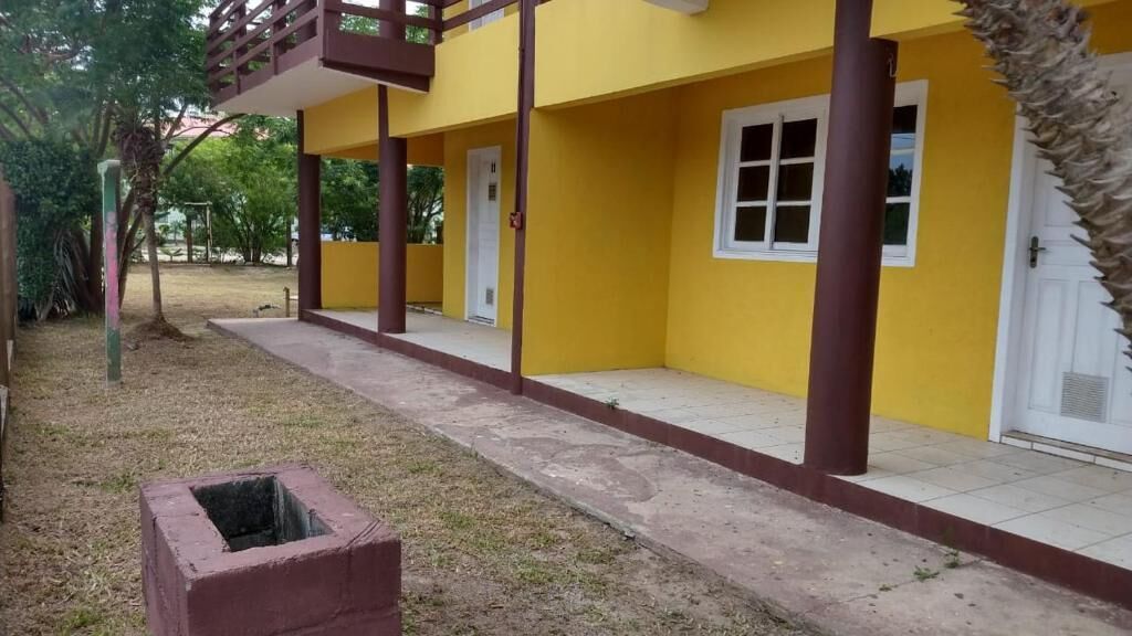 A yellow building with a covered porch and a trash bin in the foreground.