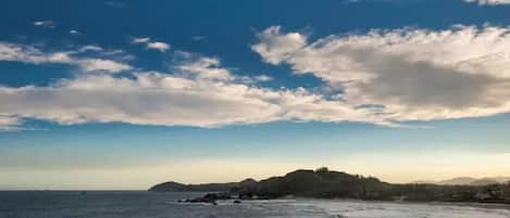 Paisagem costeira com vista para o mar e uma colina distante.