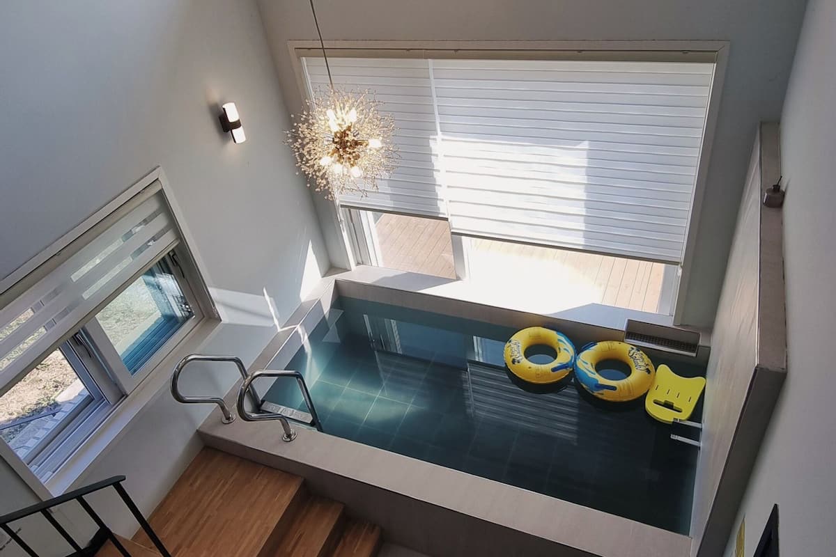Um quarto com pé-direito alto, um assento embutido na janela, uma pequena piscina e vista para o exterior.