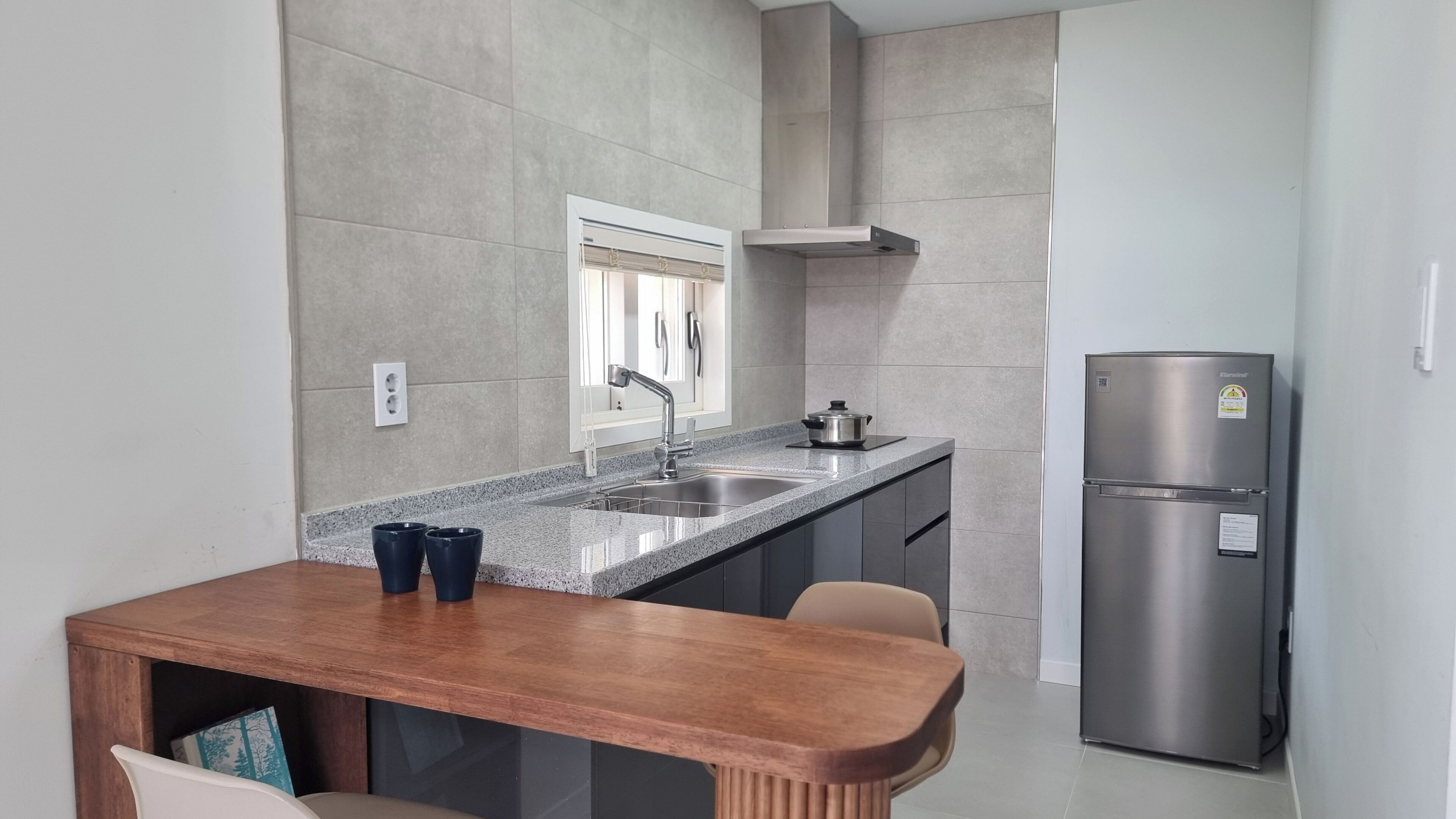 A modern kitchen with a granite countertop, stainless steel appliances, and a wooden dining table.