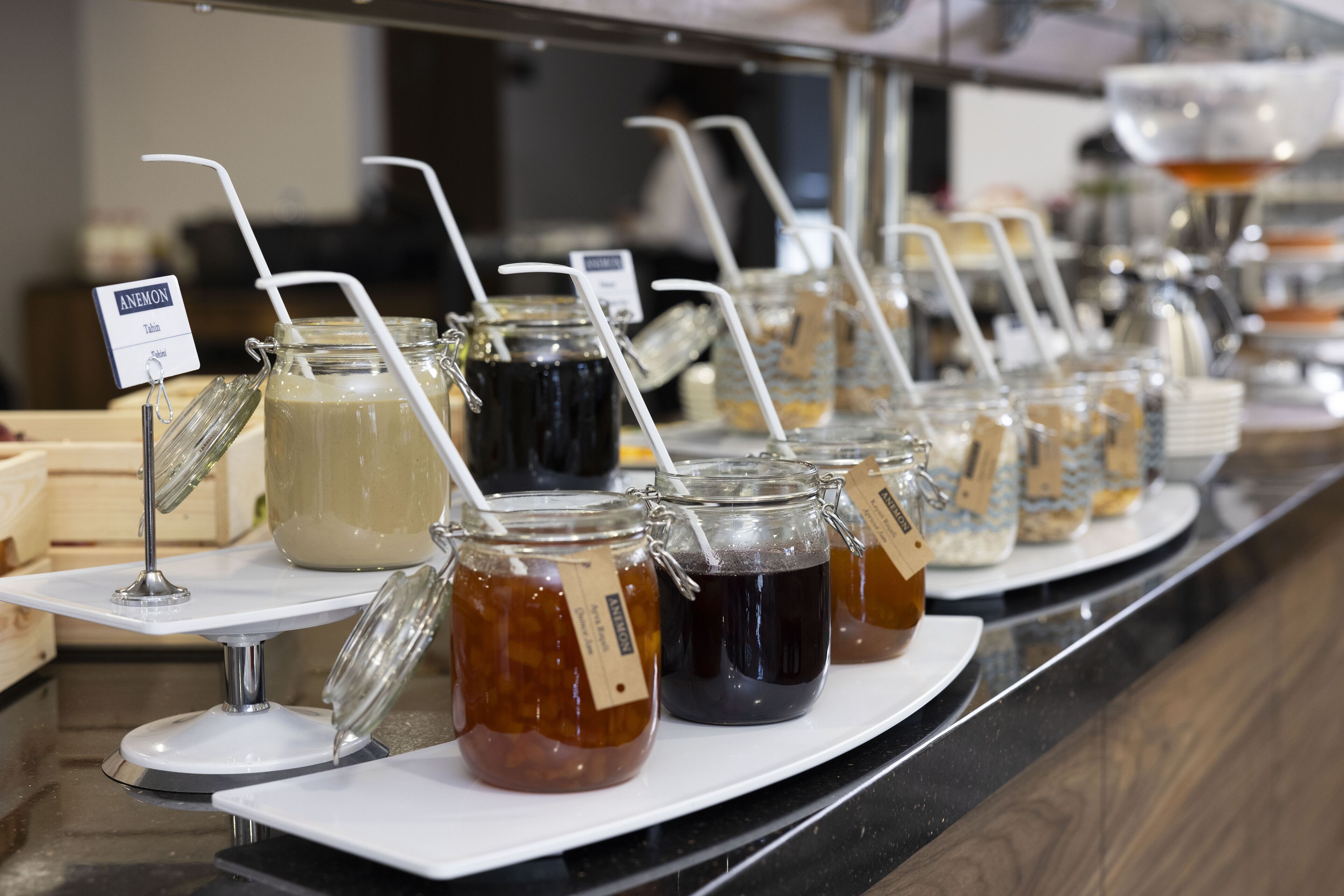 Un buffet con diversi cibi e bevande, tra cui barattoli di miele e tè freddo, su un bancone.