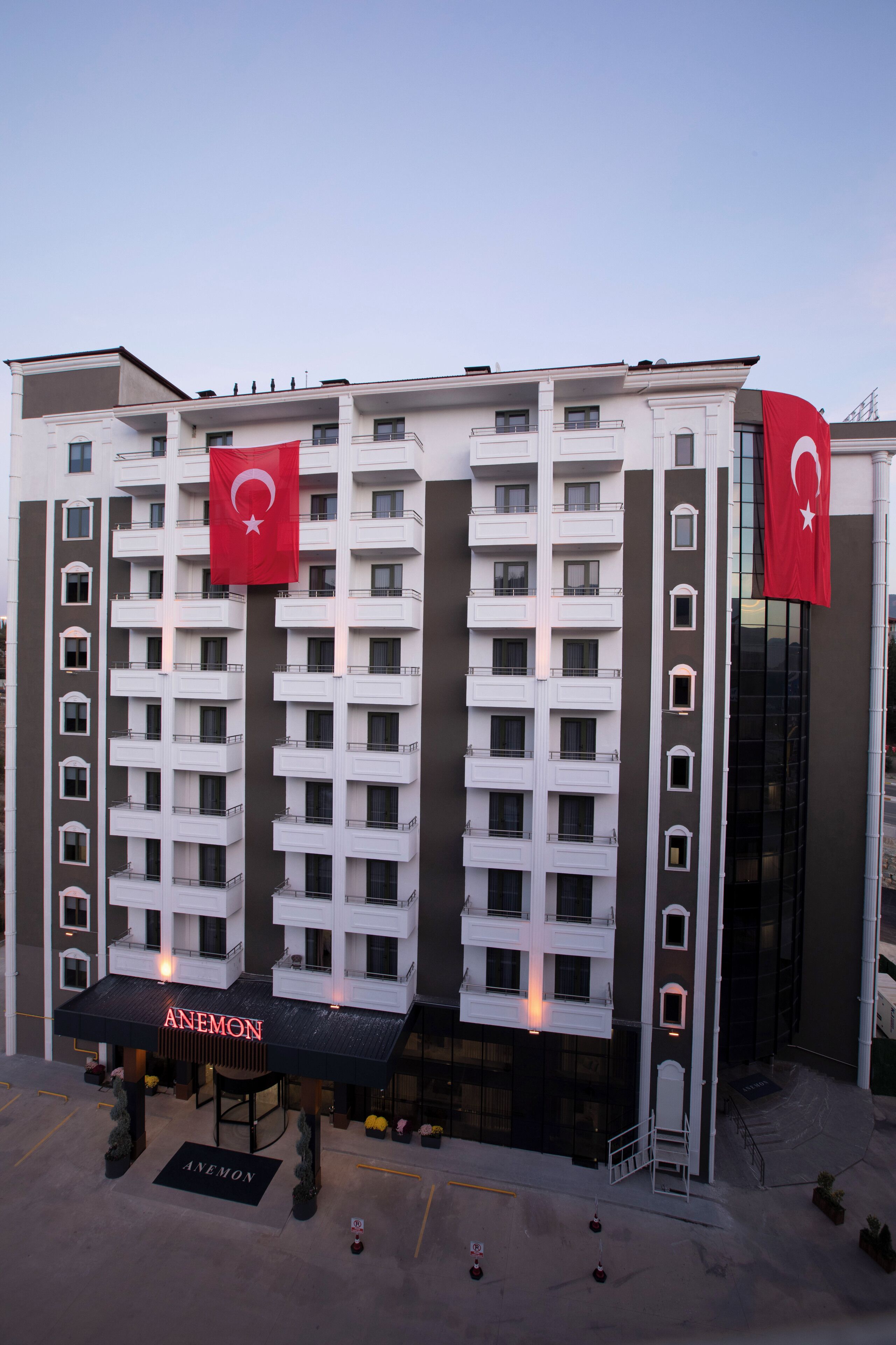 A multi-story hotel with balconies, a prominent entrance with a canopy, and Turkish flags.